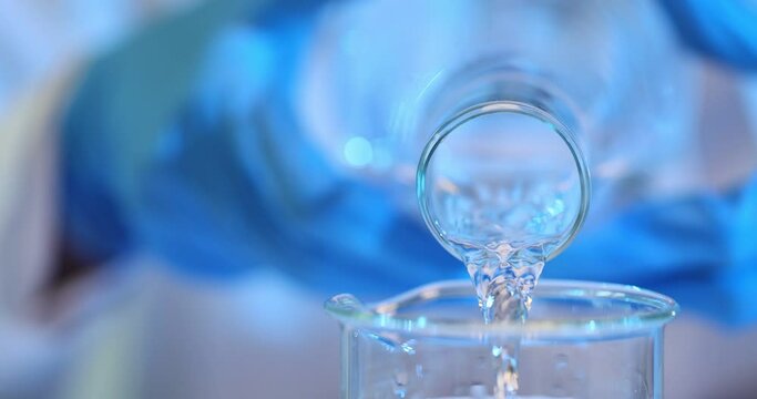 Water is poured from bottle into glass beaker in lab