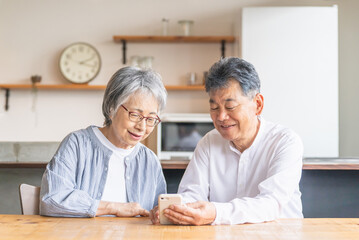 スマホ・スマートフォンのアプリを使うアジア人高齢者夫婦（笑顔・楽しい）
