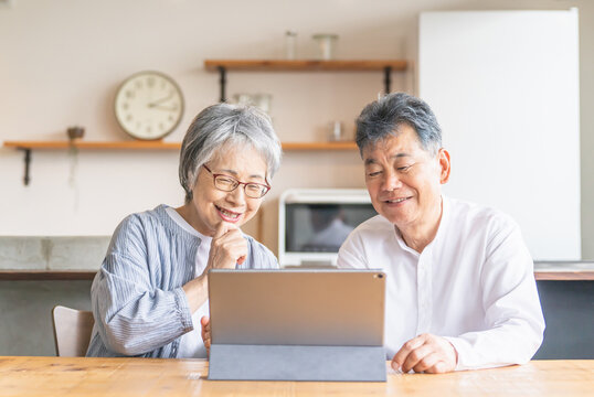 タブレットを使ってビデオ通話・テレビ電話する笑顔のシニア・高齢者夫婦
