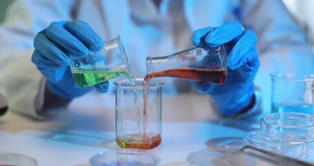 Scientist chemist conducting experiment in laboratory and mixing colored liquids