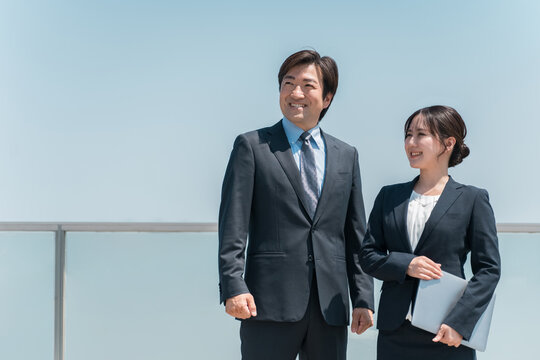 青空を見上げるスーツ姿のビジネスマン男女（希望・就職・転職・就職活動・リクルート）
