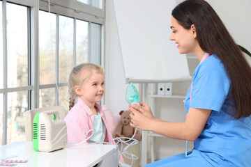 Female pediatrician with nebulizer and little girl in clinic