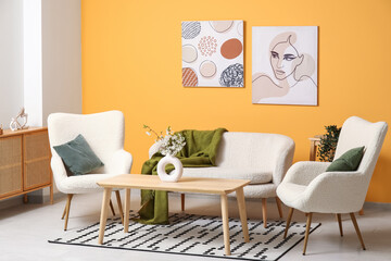 Blooming branches in vase on table in living room with orange wall