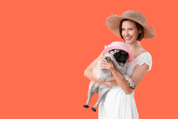 Young woman and cute pug dog in hats on orange background