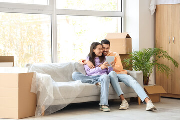 Fototapeta premium Young couple using tablet computer in room on moving day
