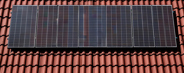 Solar panel on the roof of a house, no people, clear sky, front view. Photovoltaic panels on the roof. Saving electricity. Ecological concept.