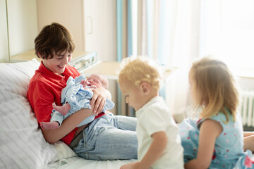 Siblings meet newborn baby in hospital