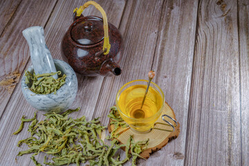 lemon verbena infusion in a glass cup with a marble mortar and pestle and a ceramic teapot with...