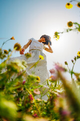 Summer mood. a young and cheerful girl posing against a background of blue sky and flowers. A...