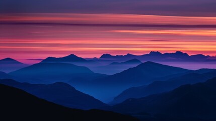 A majestic mountain range silhouetted against a darkening sky, with streaks of orange and purple painting the horizon.