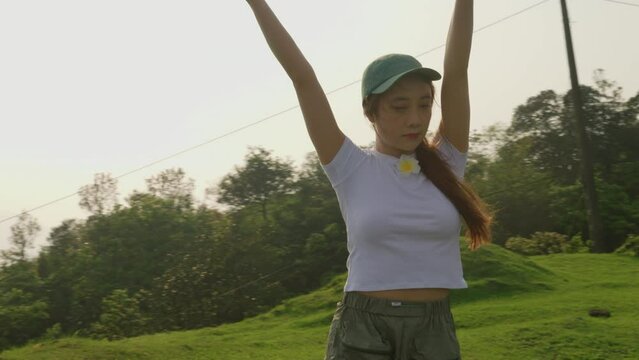 close up of asiatic young dancer dancing in slow motion on top of a hill at sunset 