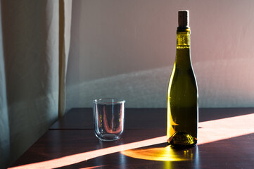 White glass and green bottle of wine with cork on table in sunlight. Classic winery cellar beautiful image