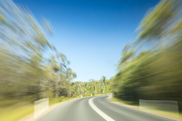long exposure photo of car driving on road with blurred trees passing by