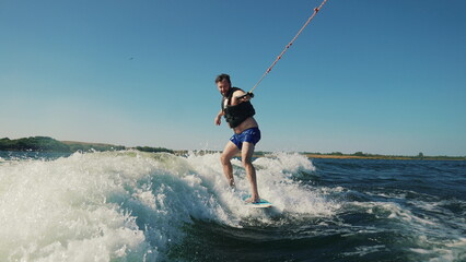 A man rides a wakeboard after a boat. Fun on the water during the hot summer on the lake.