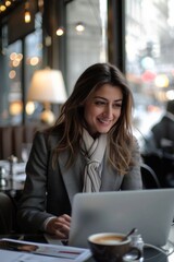 A woman is sitting at a table with a laptop and a cup of coffee