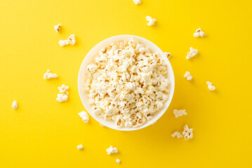 Home premiere. Overhead view captures tasty popcorn in bowl. Yellow backdrop provides space for...