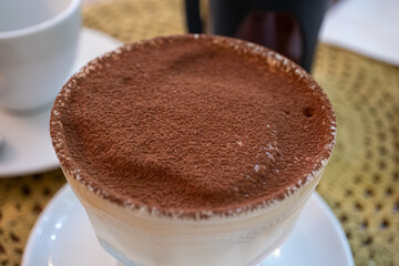 Tiramisu served in glass cup in cafe, close-up