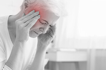 Senior woman having headache and touching her temples, suffering from migraine, free space