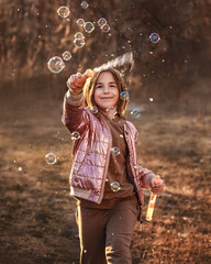 cute girl on a walk blows soap bubbles