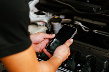 Mechanic uses smartphone to inspect car engine parts