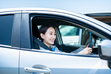 車に乗った作業着を着た笑顔の日本人女性