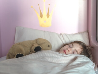 cute little girl sleeps in bed with plush toy