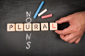 Plural nouns. Wooden block crossword puzzle and pieces of chalk on a chalkboard background