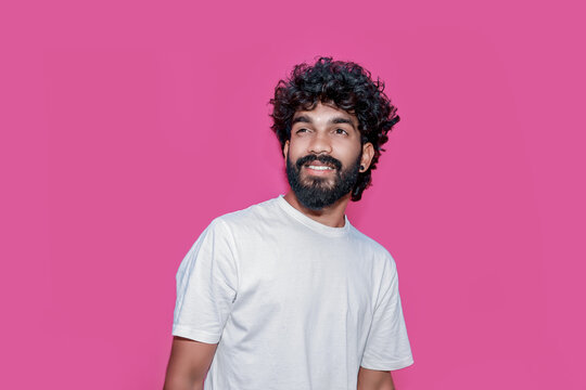 Handsome joyful smiling young indian man looking aside up and straight thinking of new good opportunities, dreaming, feeling inspired and proud standing isolated on pink background. Portrait