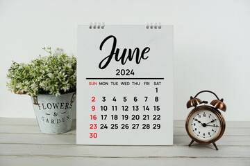 June 2024 monthly calendar with vintage alarm clock on wooden background