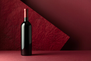 Bottle of red wine on a red background.