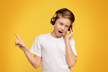 Young music lover. Teen boy enjoying great sound on wireless headphones, orange panorama background...