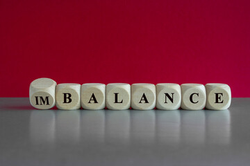 Turned a cube and changes the word imbalance to balance. Beautiful red background, grey table....