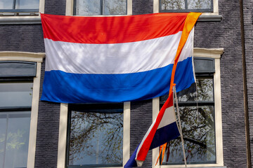 Netherlands flag with horizontal tricolour of red, white and blue, Orange flag hanging outside building, Celebration of the birthday of the King, National holiday King’s Day or Koningsdag in Dutch.
