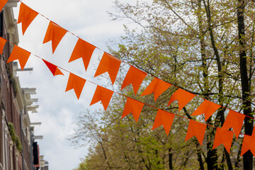 Colourful of King’s Day (in Dutch: Koningsdag) Selective focus of pennant orange flags hanging on...