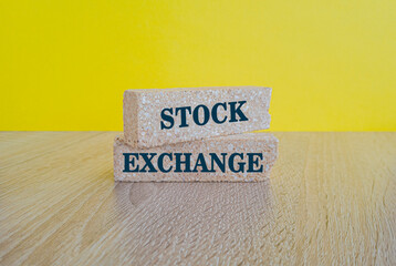 Stock exchange market symbol. Concept words Stock exchange on brick blocks on a beautiful wooden table yellow background. Business concept.