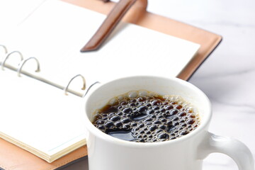 淹れたてのコーヒーを飲みながら、リング式のシステム手帳を開いて、仕事の段取りを考えているイメージ
