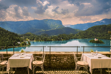 View of set up on patio of restaurant overlooking Lake Bled, Slovenia; Alps and sky with clouds in background