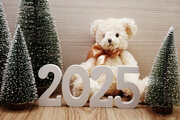 Happy New Year 2025 festive background with Christmas tree and teddy bear decoration on wooden...