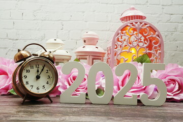 2025 Happy New Year with alarm clock with Roses and pink lantern Decoration on wooden background