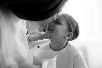 mother and daughter kiss before breakfast in home kitchen