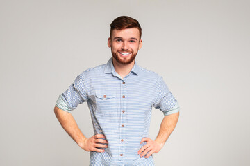 Portrait of smiling guy with hands on hips on beige background, panorama, copy space
