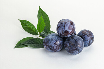 Raw purple plums heap with leaves