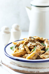 Penne Pasta baked with Meat on bright wooden Background. Close up.