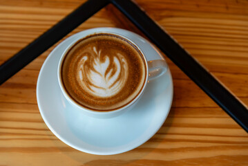 Hot latte art coffee cup on wooden table