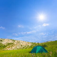 green touristic tent among green mountain under a sparkle sun, summer mountain travel scene