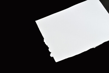 White sheet with jagged edges on a black background.