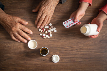 Elderly woman and child hands showing medical pills.