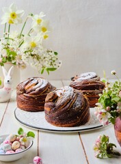 Two-layer vanilla chocolate Easter yeast cake craffin on a ceramic board on a light wooden background. Easter baking, treats, concept.