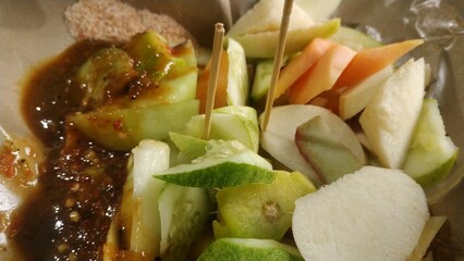 Rujak buah or indonesian mixed fruit salad, served with spicy brown sugar sauce and ground peanuts