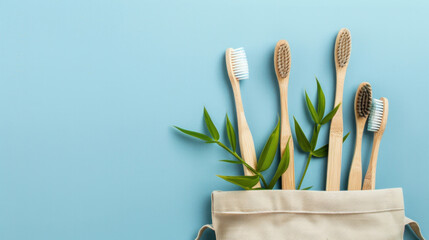 bamboo toothbrushes with colorful bristles in a beige canvas bag, accented with green leaves on a light blue background